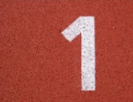 A white number 1 painted on a red running track