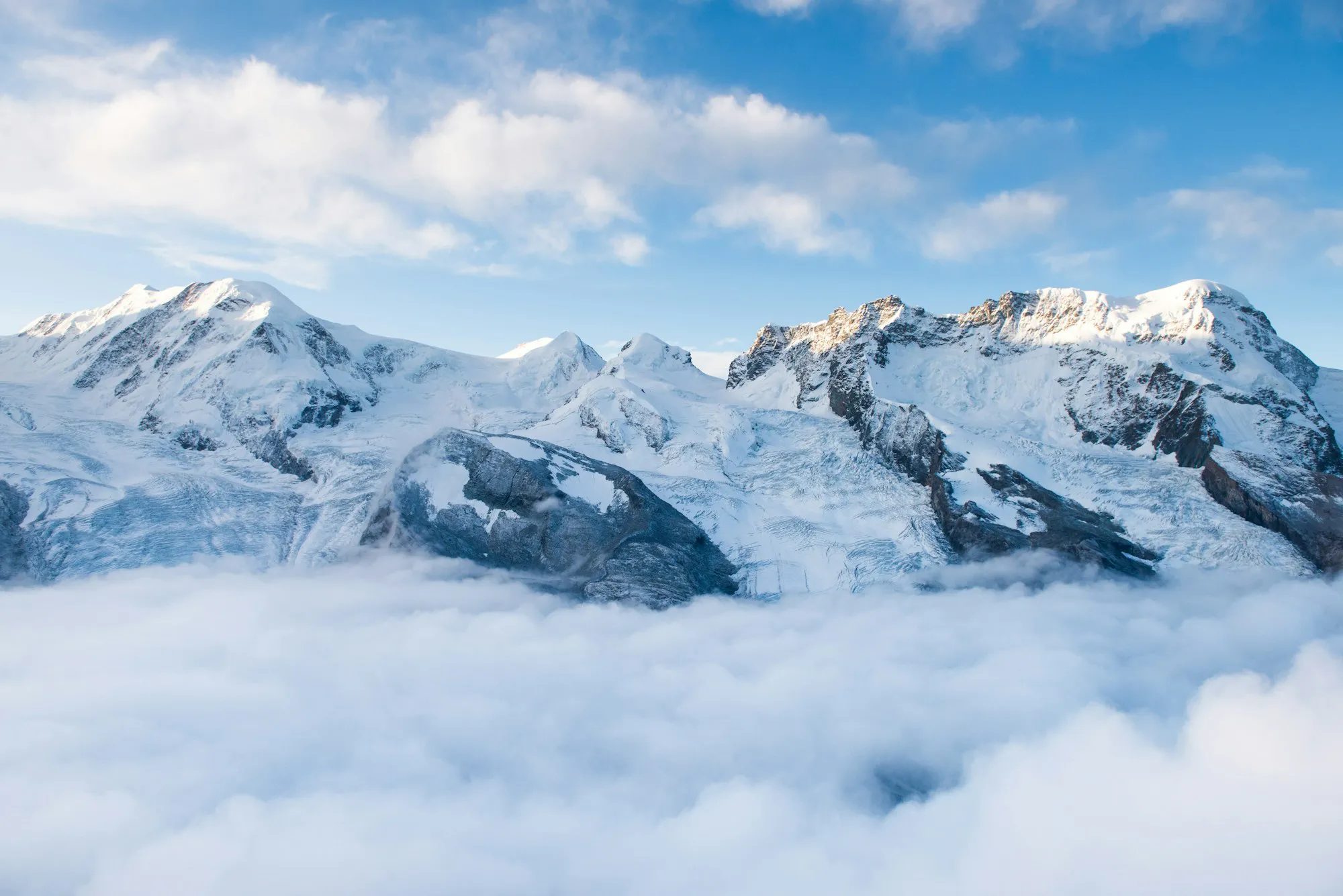 Snowy Alpine peaks above a sea of clouds as the Mac desktop wallpaper, with Snippet's notch panel open at the top